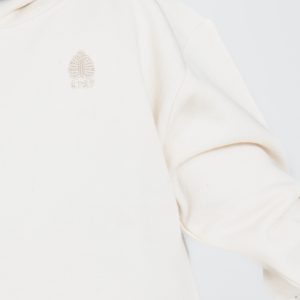 Detalle del logotipo bordado Indiana 1727 en sudadera infantil de algodón orgánico beige.