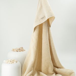 Albornoz beige de algodón orgánico Indiana 1727 colgado en percha de madera.