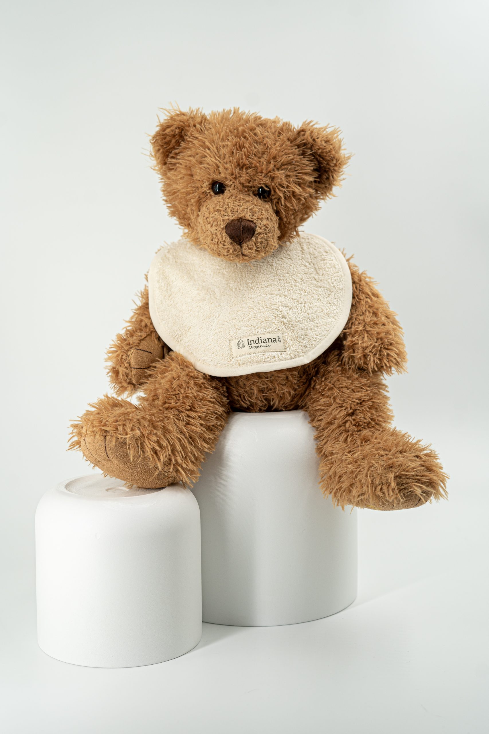 Babero redondo de la colección Baby & Family de Indiana 1727, confeccionado en algodón 100% orgánico certificado. Osito de peluche con babero beige de algodón orgánico Indiana 1727.